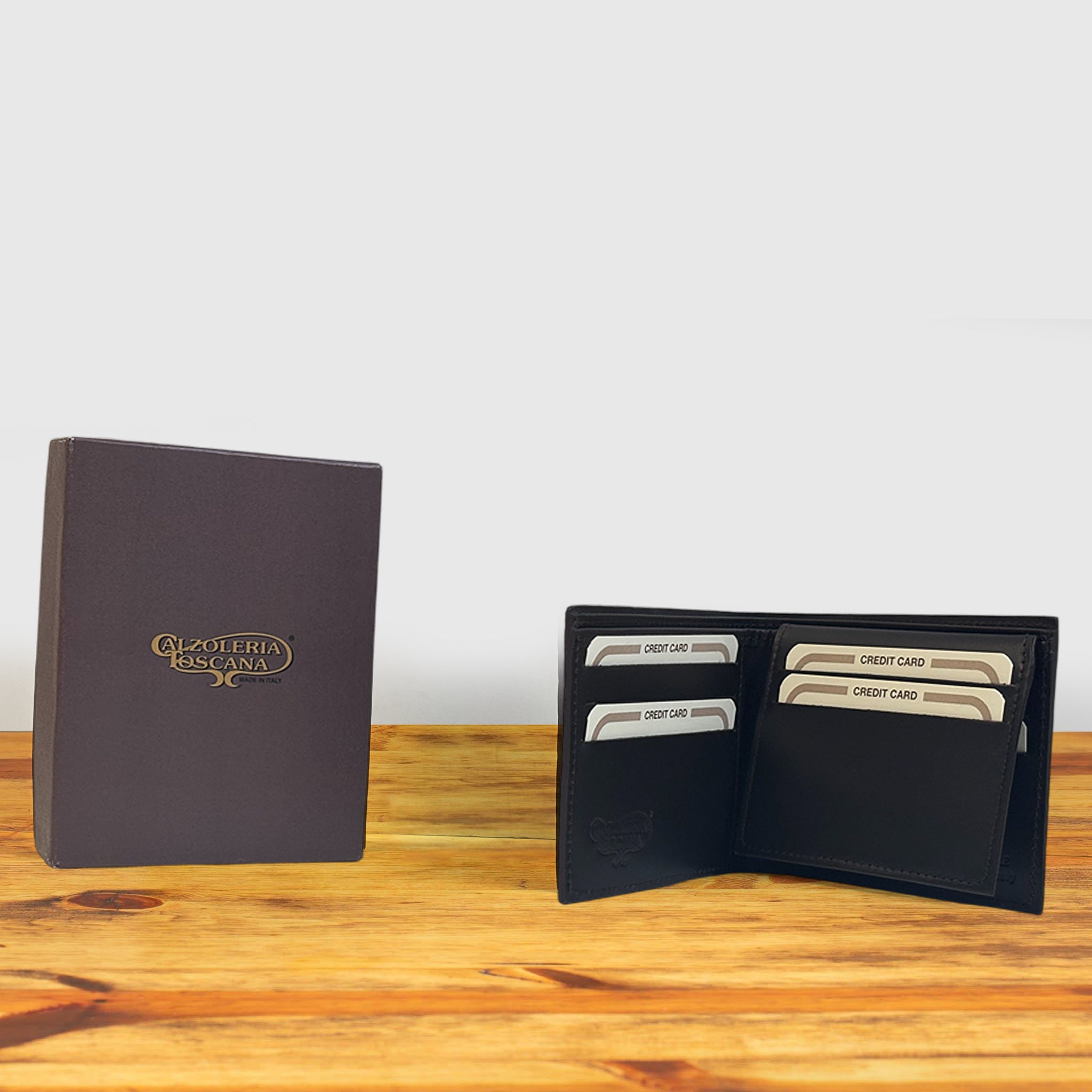 Black wallet with credit cards and a box on a wooden surface and light gray background