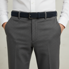 Gray dress pants with a blue belt and white shirt on a neutral background