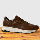 A Moor leather Vibram sneaker with textured overlays and a thick white midsole, displayed on a wooden surface against a light gray background.