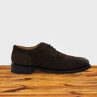 Charcoal suede dress shoe on a wooden surface with a light gray background