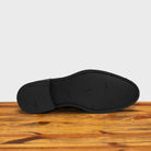 Outsole of the Charcoal suede dress shoe on a wooden surface with a light gray background