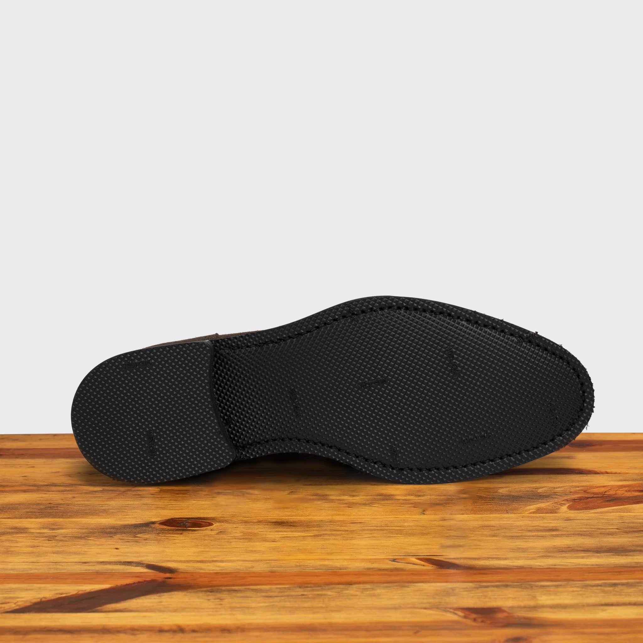 Outsole of the Charcoal suede dress shoe on a wooden surface with a light gray background