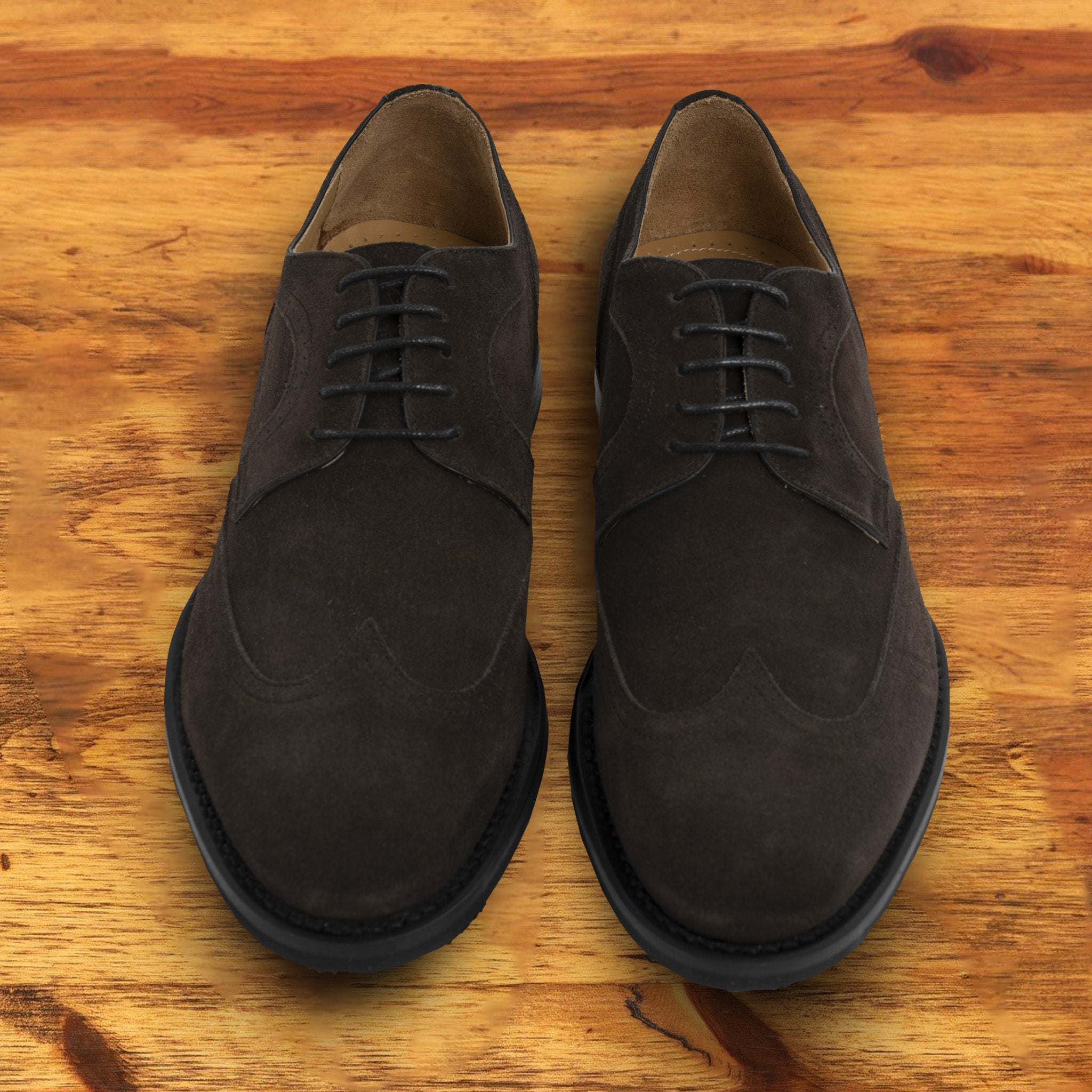 Charcoal suede dress shoe on a wooden surface