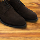Charcoal suede dress shoe on a wooden surface
