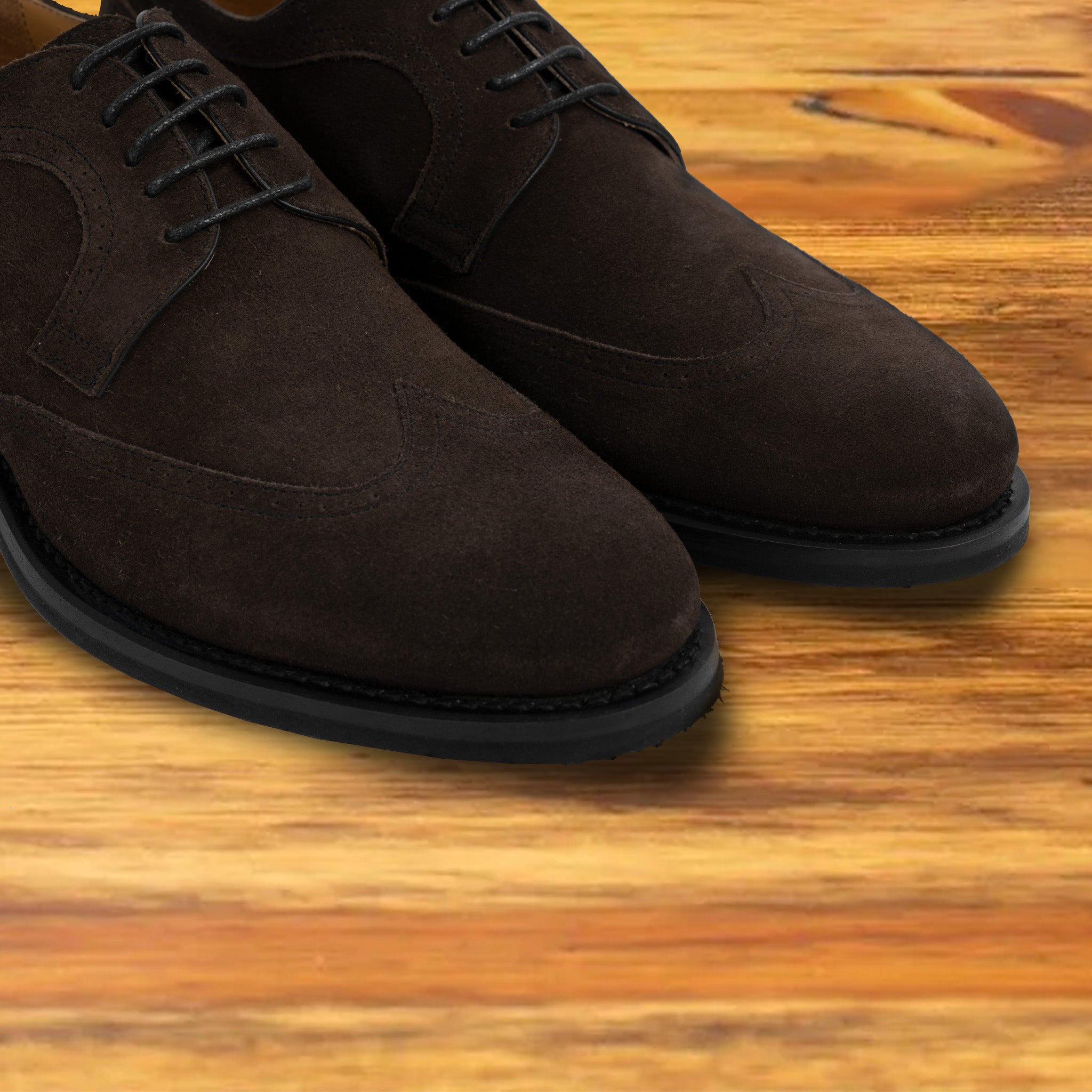 Charcoal suede dress shoe on a wooden surface