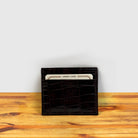 Brown crocodile-patterned cardholder with credit cards on a wooden surface and light gray background