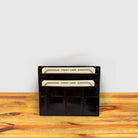 Dark Brown crocodile-patterned cardholder with credit cards on a wooden surface and light gray background