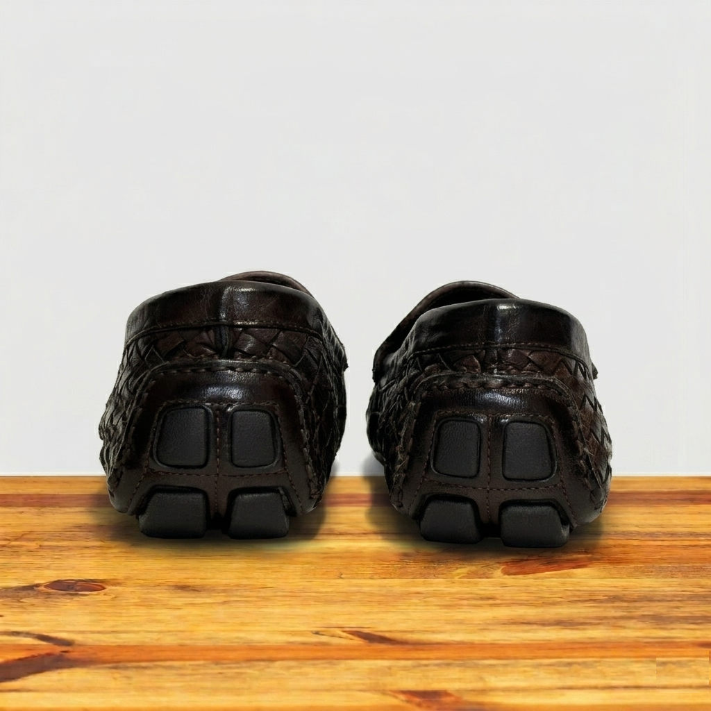 Backside Pair of Dark Brown loafer shoe with woven pattern on a wooden surface