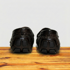 Backside Pair of Dark Brown loafer shoe with woven pattern on a wooden surface