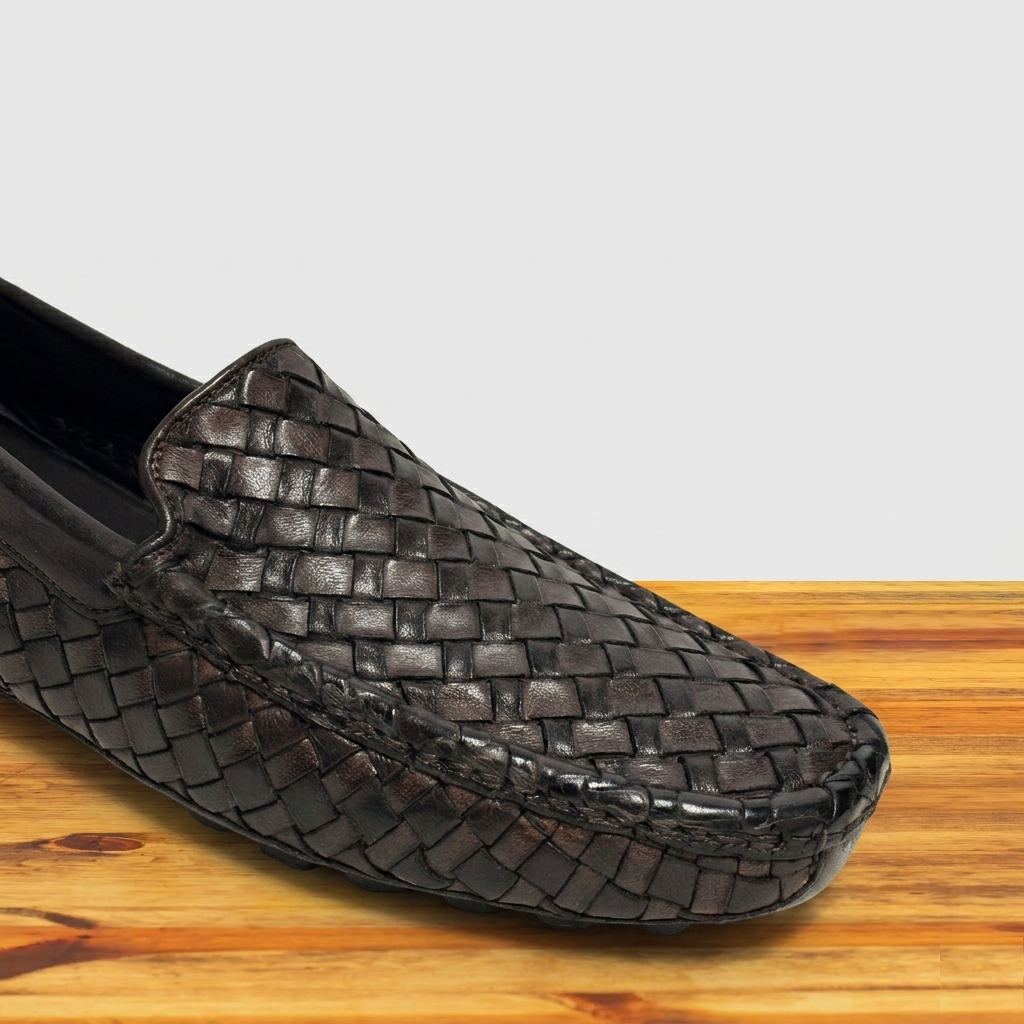 Woven Dark Brown loafer shoe on a wooden surface with a light gray background