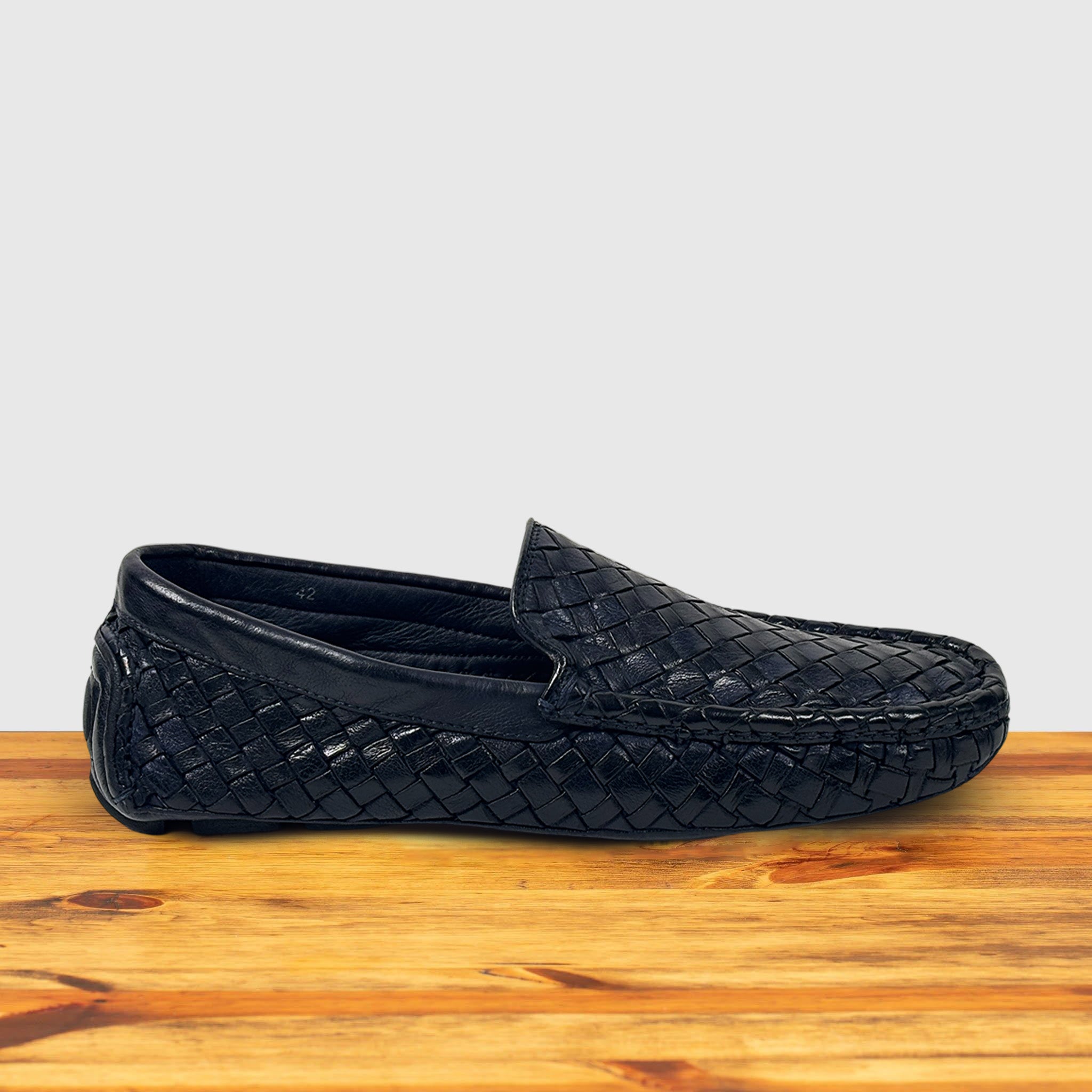 Navy Blue loafer shoe with woven pattern on a wooden surface