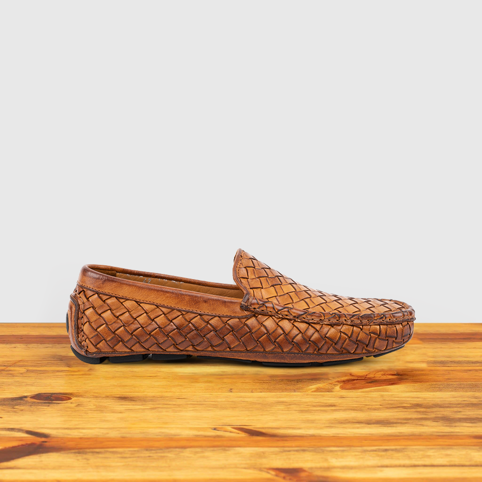 Brick loafer shoe with woven pattern on a wooden surface