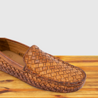 Brick loafer shoe with woven pattern on a wooden surface