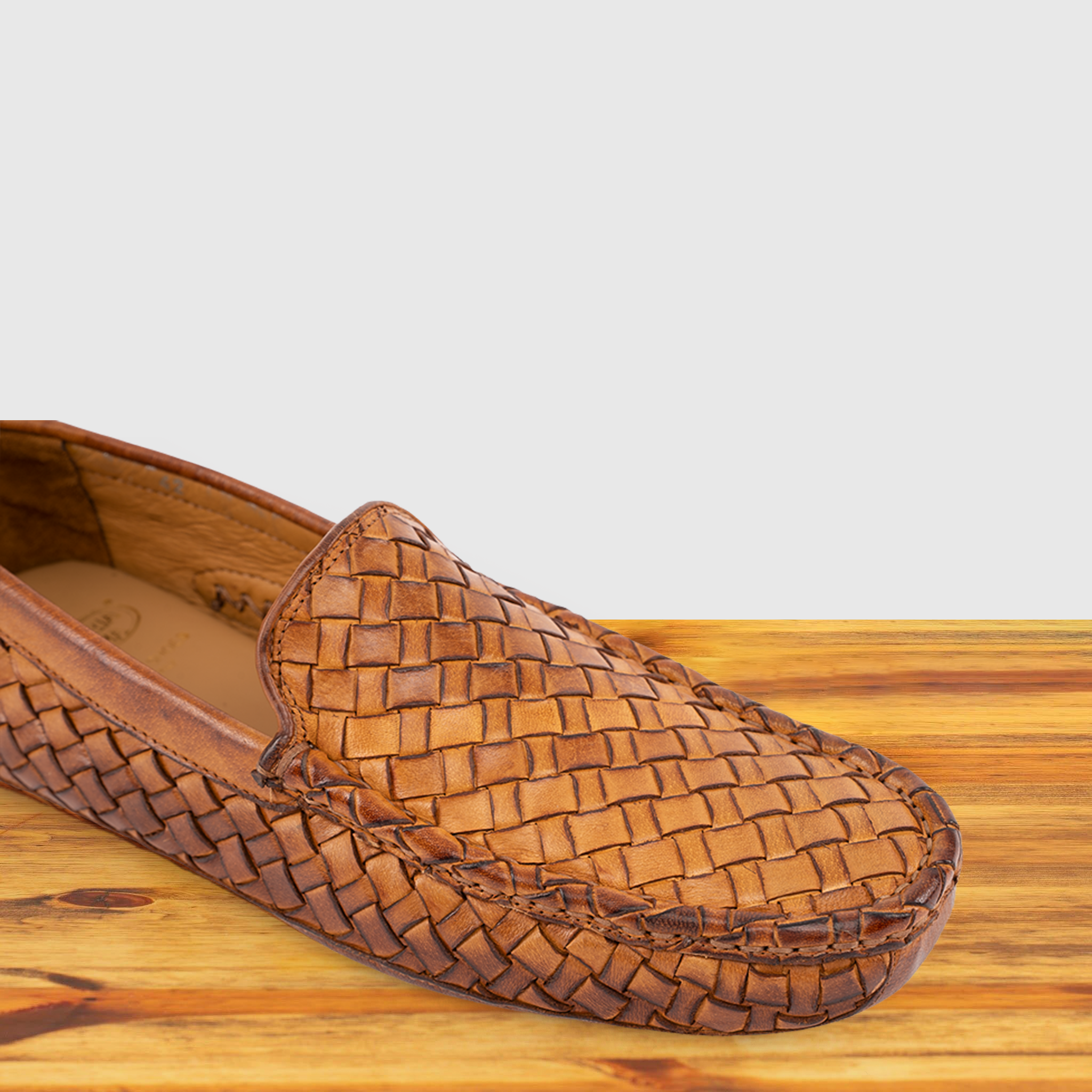 Brick loafer shoe with woven pattern on a wooden surface