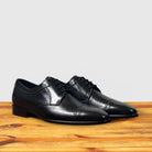 A pair of Black leather dress shoe on a wooden surface with a light gray background