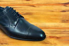 Black leather dress shoe on a wooden surface