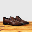 Pair of Brown leather dress shoe on a wooden surface with a light gray background