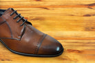 Brown leather dress shoe on a wooden surface