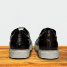 Black leather shoes with white soles on a wooden surface and light gray background