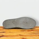 Dark Brown shoe sole on a wooden surface with a white background