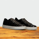 Pair of Dark Brown sneakers with white soles on a wooden surface
