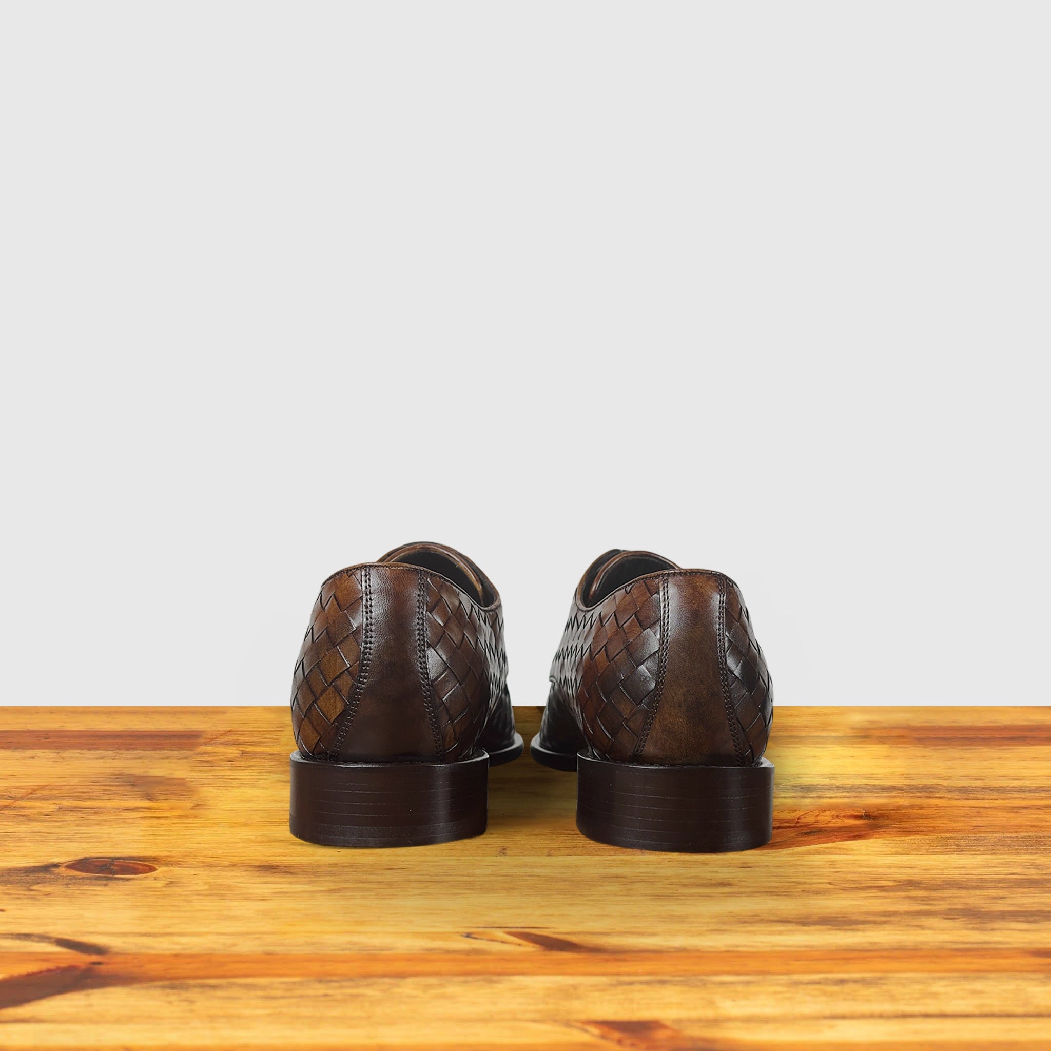 Pair of brown leather shoes on a wooden surface with a light gray background