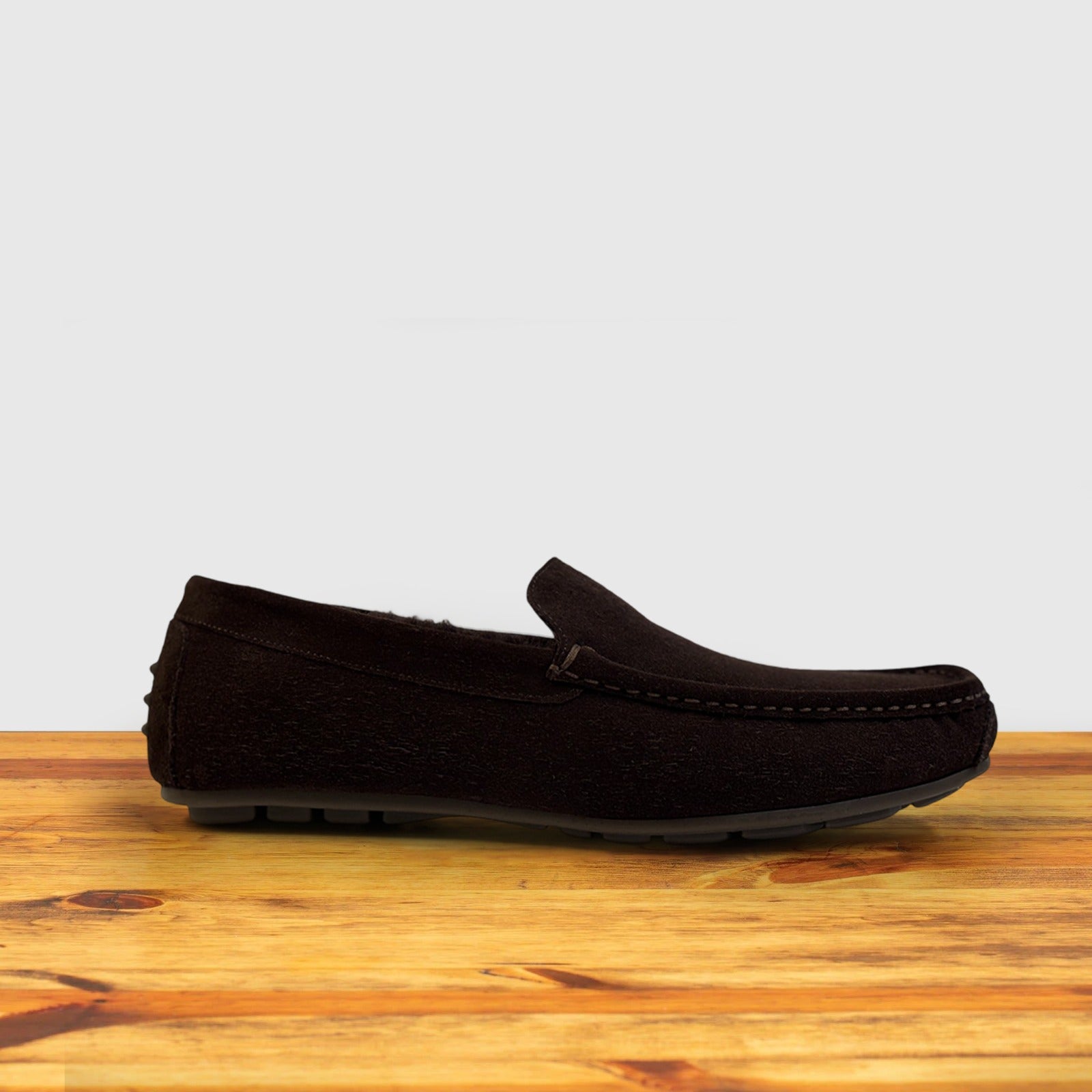 Brown loafers on a wooden surface with a light gray background