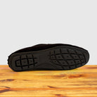 Outsole of brown loafers shoe on a wooden surface with a light gray background