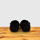 Pair of brown loafers on a wooden surface with a light gray background