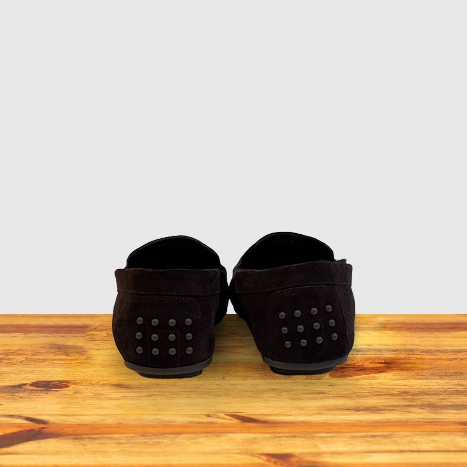 Pair of brown loafers on a wooden surface with a light gray background