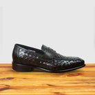 A pair of Brown woven loafer shoe on a wooden surface with a light gray background