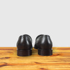 A pair of Brown woven loafer shoe on a wooden surface with a light gray background