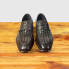 A pair of Brown woven loafer shoe on a wooden surface with a light gray background