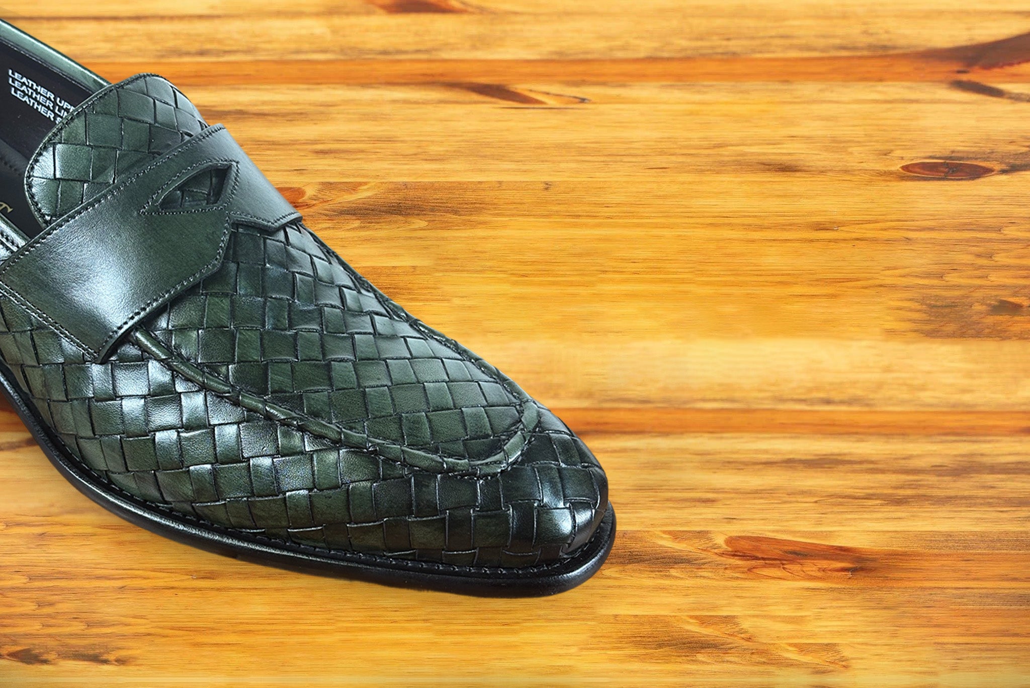 Green woven loafer shoe on a wooden surface