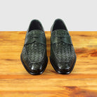 A pair of Green woven loafer shoe on a wooden surface with a light gray background