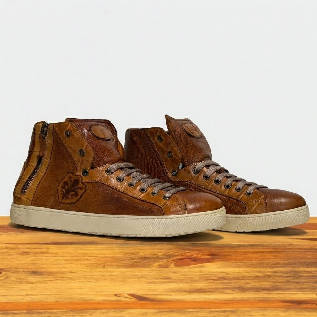 Pair of brown leather high-top sneakers on a wooden surface with a light gray background