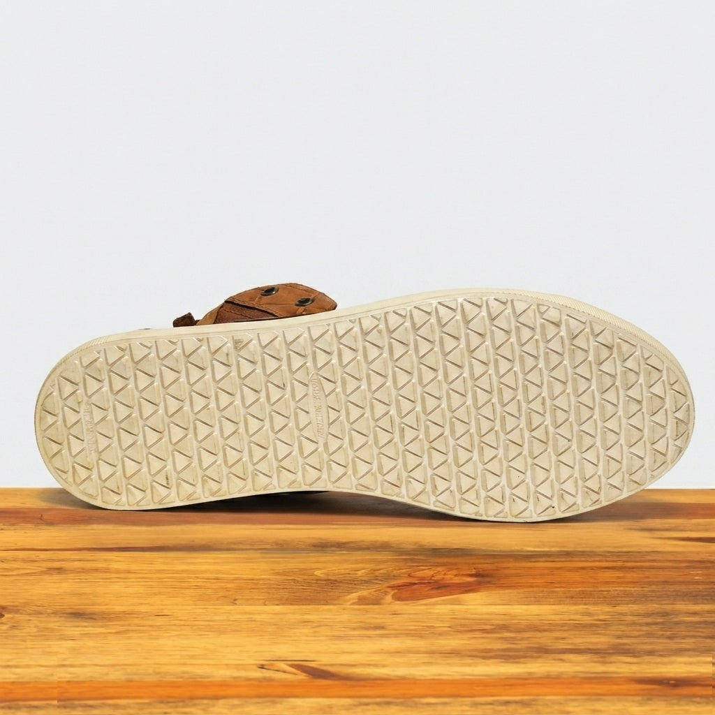 Close-up of a shoe sole with a textured pattern on a wooden surface.