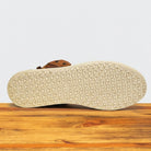 Close-up of a shoe sole with a textured pattern on a wooden surface.