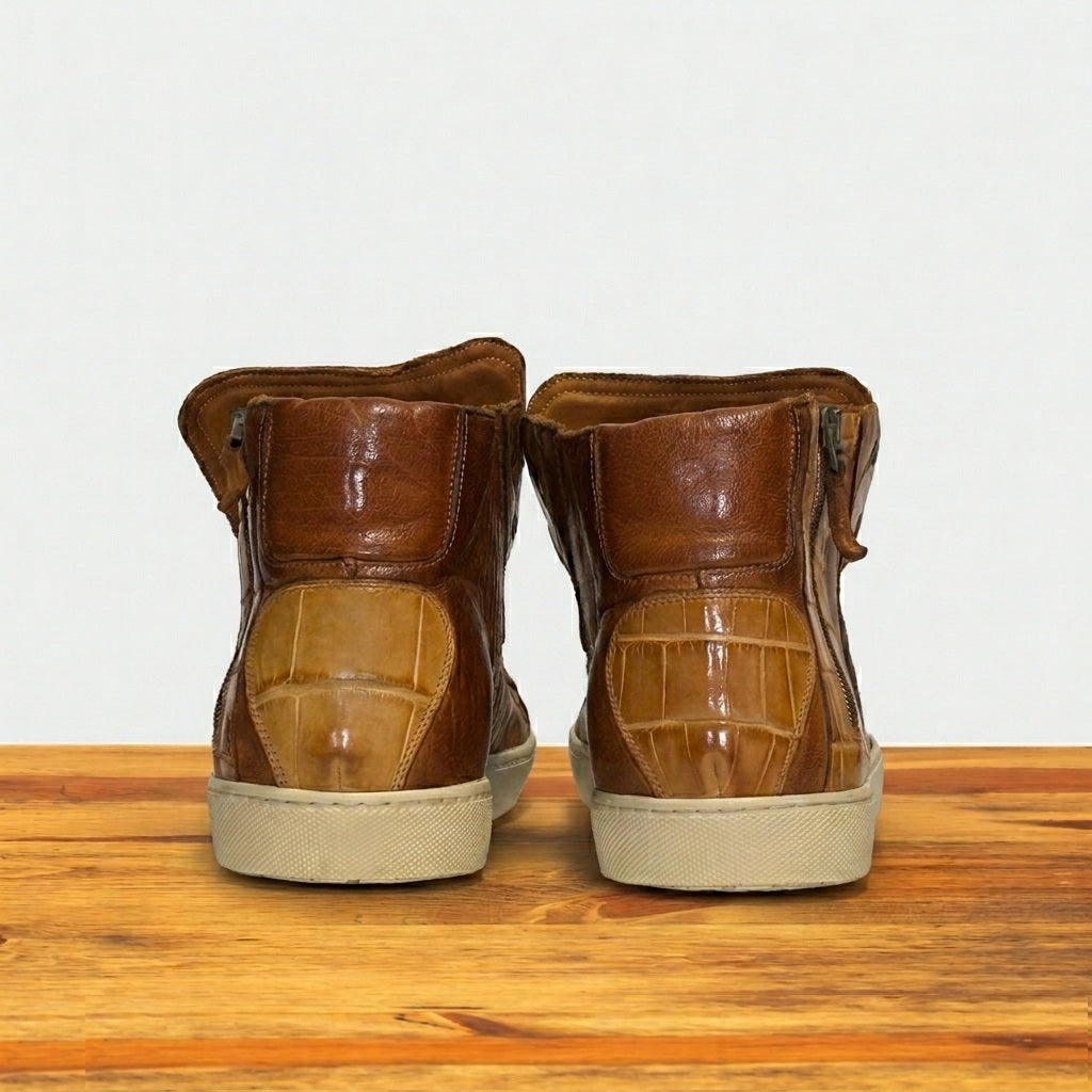 Pair of brown leather boots on a wooden surface with a light gray background