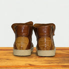 Pair of brown leather boots on a wooden surface with a light gray background