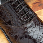 Close view of brown alligator leather dress shoes on a wooden surface