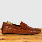 A single Burnt Orange Genuine Crocodile leather loafer driving shoe, resting on a wooden surface against a light gray background.