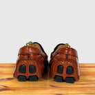 A pair of Burnt Orange Genuine Crocodile leather loafers shown from the back, resting on a wooden surface against a light gray background.