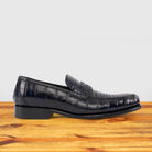 Blue leather loafer on a wooden surface with a light gray background