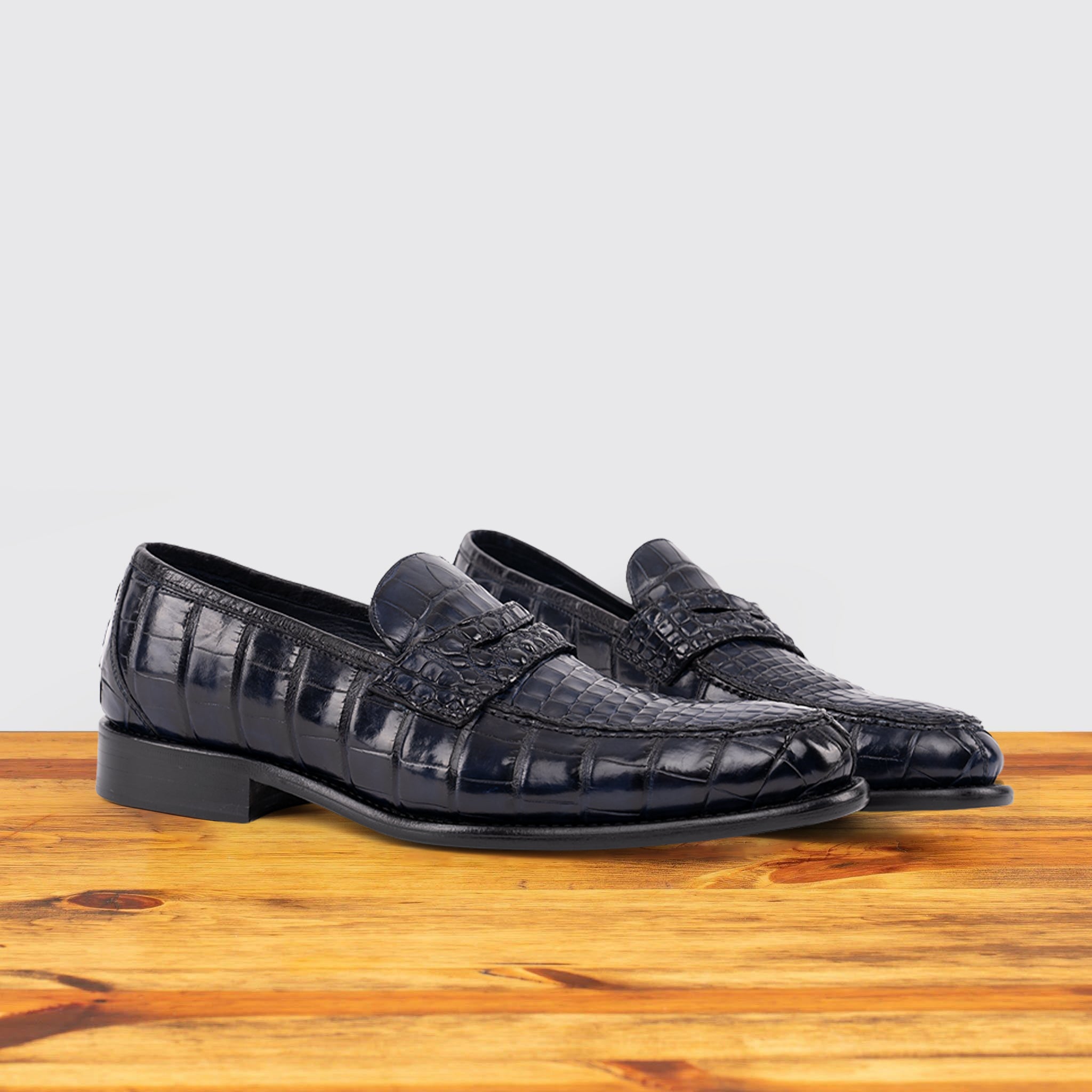 A Pair of Blue leather loafer on a wooden surface with a light gray background