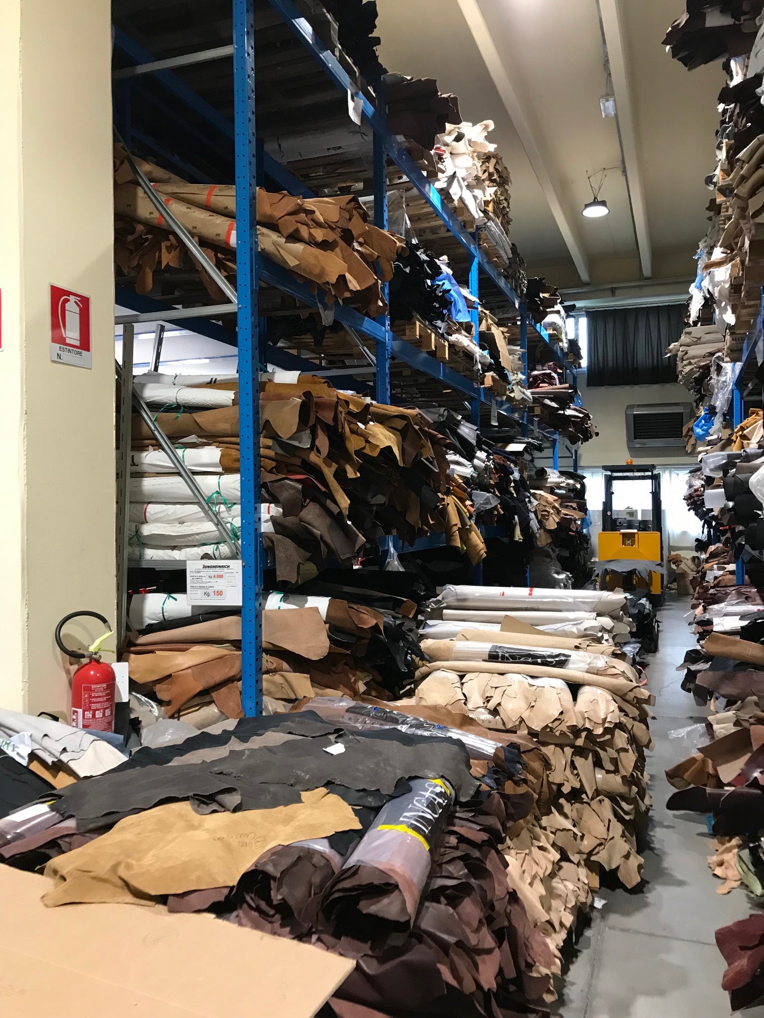Premium Italian leather hides in multiple colors stacked in the Calzoleria Toscana factory, raw materials for handcrafted men's shoes