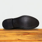 Brown leather shoe sole on a wooden surface with a light gray background