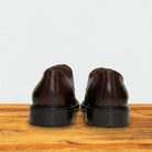 Pair of brown leather shoes on a wooden surface with a light gray background