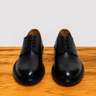 Pair of black leather dress shoes on a wooden surface with a white background