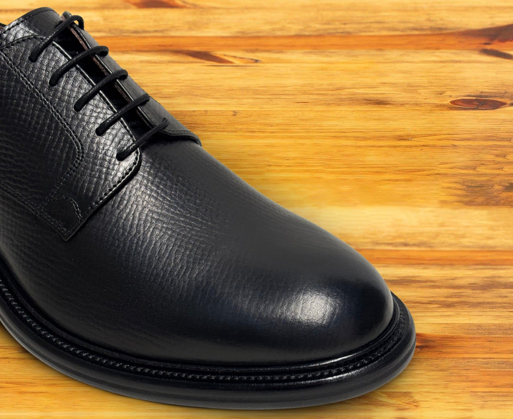 Black leather dress shoe on a wooden surface
